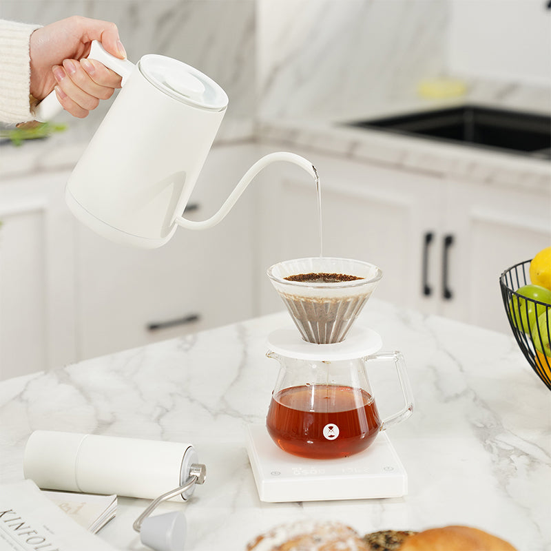 person pouring water from Timemore Fish Smart Kettle into pour over dripper