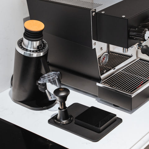 DF54 Coffee Grinder next to an espresso machine on a sleek countertop setup, showcasing modern coffee equipment.